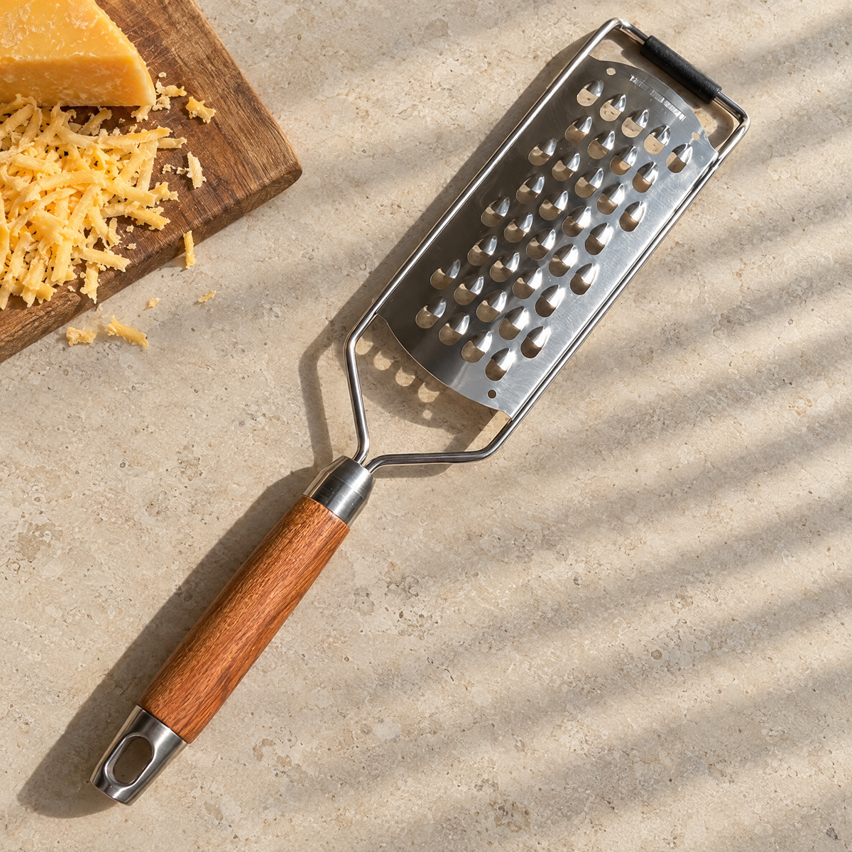 Acacia grater on a limestone counter next to grated cheddar