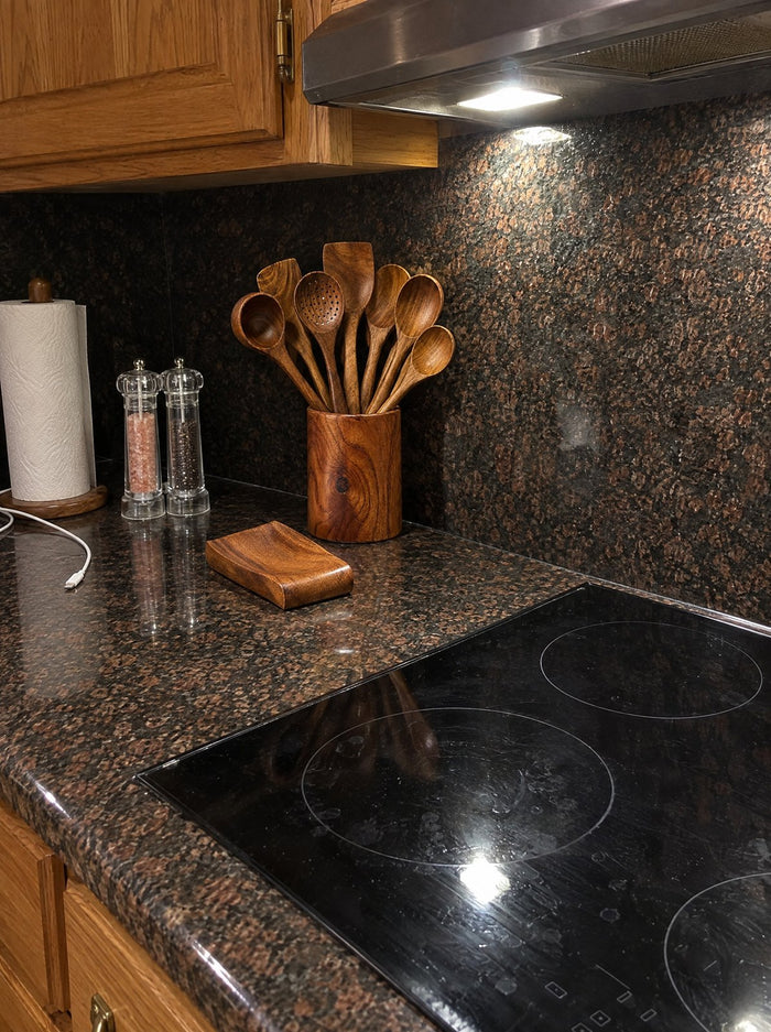 Teak utensils in their holder with spoon rest on a granite counter