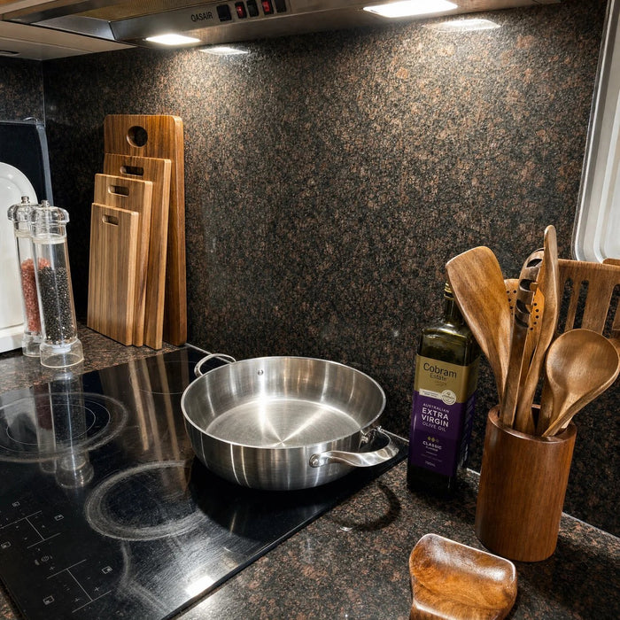 Wooden boards and utensils next to a stainless pan on an induction hob